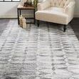 Beckett diamond rug styled in a room with beige tufted chair and side table on dark floor