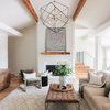 Black dots framed art hanging above a white brick fireplace in a bright living room with wood accents