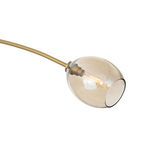 Close-up on amber champagne glass globe with visible filament bulb inside attached to brass fixture