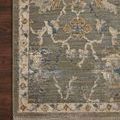 Close-up of rug corner showing detailed floral design, soft texture, and short fringe on dark hardwood