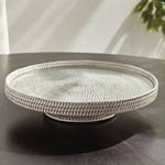 Serving stand on dark table with sunlit wall and foliage in background