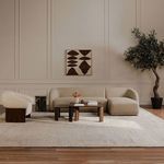 Living room scene showing Otto accent chair with matching textured sofa, wooden tables, and artwork