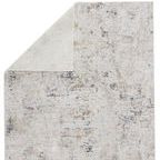 Rug corner flipped over revealing the plain light gray backing contrasting the abstract pattern