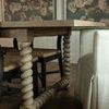 Close side angle highlighting parqueted top edge and spiral legs beside woven chairs and beige chair