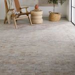 Section of rug beneath wooden chair with brown seat showcasing blended shades and texture