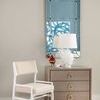 Stanford side table styled in a room with a white chair, large mirror, and soft neutral walls