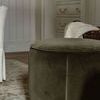 Close-up side angle of single olive velvet ottoman with piping detail in neutral room