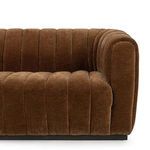 Detailed close-up of one rounded armrest and vertical channel stitching on rich brown velvet