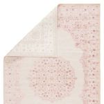 top-view of pink and white rug corner with curled edge revealing the rug backing