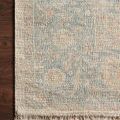 close-up on rug’s edge showing fringe and intricate pattern on a dark wood floor