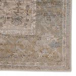 Close-up detail of rug edge showing intricate faded floral and medallion patterns in gray and gold hues