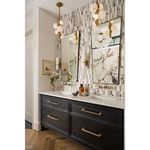 Side view of bathroom vanity with black cabinetry, brass Styx Vertical Pendants, and patterned tile wall
