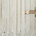 Lower section close-up of straight and curved clear glass bars partially obscuring glowing bulbs behind
