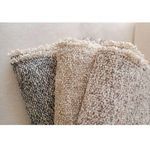Close-up of soft woven textures and fringed edges of Brentwood Throws draped over beige upholstery