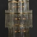 Chandelier glowing warmly viewed head-on with light bulbs visible through clear textured glass bars