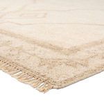 Close-up on textured fringe and plush pile showing wool fibers in beige and cream tones