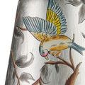 Close-up of bird with blue and yellow wings perched on painted branch on silver chandelier shade