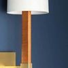 Close-up of the sconce’s white linen shade and brass arm mount on a blue wall