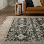 Angled view of navy cream rug next to tan leather sofa and round wood side table