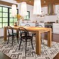 Rug and dining setup with pendant lamps hanging over table in kitchen with stainless steel appliances