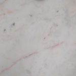 Close-up of honed white marble tabletop displaying subtle veining patterns