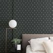 Wallpaper applied on a bedroom wall with gray upholstered bed, white bedding, and modern lamp