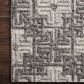 Close-up of Ehren Charcoal/Fog rug corner placed on dark wood floor, highlighting wool texture and geometric pattern