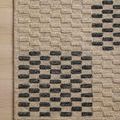 Close-up of rug corner laying flat on light wooden floor highlighting striped geometric design