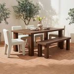 Outdoor patio setting with the dining table paired with four white fabric chairs and a teak bench on brick floor