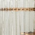 Close-up of clear textured glass bars attached to antique brass frame with visible screws and light bulb inside