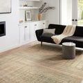 Bowery beige multi rug styled in living room with black sofa, round concrete table, and light decor