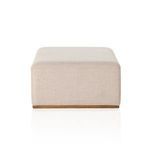 Ottoman corner and edge view showing upholstery detail and wood base finish