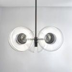 Chandelier shown hanging against a white wall with visible black brass hanging rod