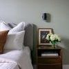 Side angle of Kira 2 Light Wall Sconce above nightstand featuring flower vase and framed artwork against green wall