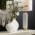 Starburst mirror styled on wall above console with white ceramic vases and ribbed table lamp