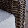 Close-up of thick dark brown resin wicker texture and light gray fabric cushion corner