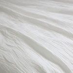 Close-up of draped coverlet highlighting soft folds and textured geometric cotton weave