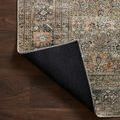 Rug corner folded back revealing black non-slip backing and stitched edges on wood floor
