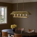 Chandelier installed over dark wood dining table in warm brown room setting with leather chairs