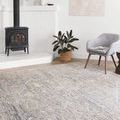 Lucia rug shown in a bright room near wood stove and modern grey armchair with indoor plants