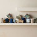 Colorful woven lampshades arranged in a horizontal row on a light wall shelf