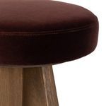 Close-up of the plum velvet seat upholstery edge and stitching on the bar stool