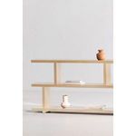 Partial side view of Miri Small Shelf showing two decorative vases and stacked books on middle shelf