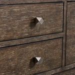 Close-up of textured faceted aluminum drawer knobs on wire-brushed wood surface