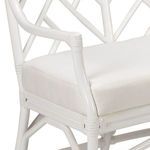 Close-up of white rattan armrest and cushioned seat with woven rattan details