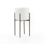 Small white cylindrical outdoor planter with slender bronze metal legs in modern design