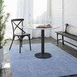 Rug in outdoor setting under small round table with black chair and white wine glasses
