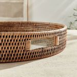 Close-up on tray handle with sunlight highlighting natural rattan texture and weave