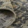 Underside of a rug corner folded over, showing dense hand-loomed backing in muted colors