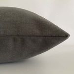 Side view close-up showing fine woven texture and precise stitching on gray pillow cover